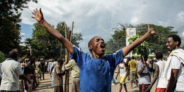 QUALITY REPEATA man raises his arms as people celebrate in the streets of Bujumbura on May 13, 2015 following the radio announcement by Major General Godefroid Niyombare that President Nkurunziza was overthrown. Burundi's presidency said an attempted coup by a top general had 'failed' on May 13 and pro-president Burundi troops at state broadcaster fire warning shots over the heads of hundreds of protesters. Nkurunziza flies home to Burundi on May 13 hours after an army officer announced a coup while he was attending a regional crisis meeting in neighbouring Tanzania. AFP PHOTO / JENNIFER HUXTA (Photo credit should read Jennifer Huxta/AFP/Getty Images)