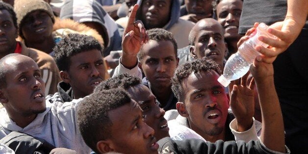 Migrants from sub-Saharan Africa receive water as they wait at a detention center on May 17, 2015 in Tripoli, after being arrested in Tajoura, a coastal town east of the capital, as they prepared to board boats for Europe. Libyan authorities arrested at dawn 400 illegal migrants, including several pregnant women, officials said. AFP PHOTO / MAHMUD TURKIA (Photo credit should read MAHMUD TURKIA/AFP/Getty Images)