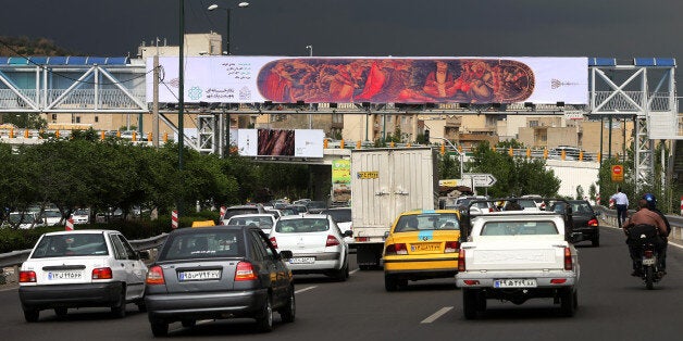 In this photo taken on Sunday, May 10, 2015, cars drive under a billboard showing a copy of an old painting which decorates a pen case, over a highway of Tehran, Iran. In an unusual move by Tehran's mayor, hundreds of copies of famous artworks - both of world masters and Iranian artists - have been plastered on some 1,500 billboards across the city, transforming the Iranian capital into a gigantic, open-air exhibition. (AP Photo/Ebrahim Noroozi)