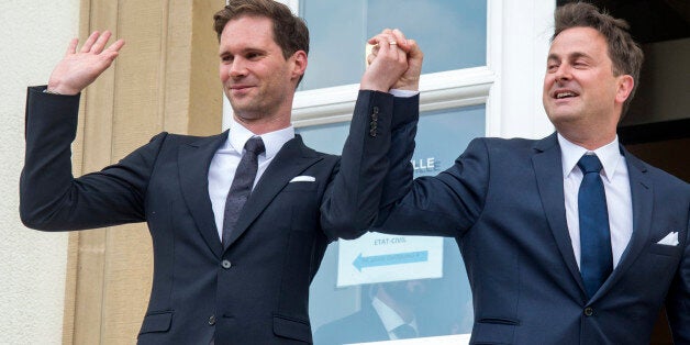 Luxembourg's Prime Minister Xavier Bettel, right, holds up the hand of his partner Gauthier Destenay, with a wedding band on his finger, as they leave the town hall after their marriage in Luxembourg, on Friday, May 15, 2015. The marriage comes one year after the parliament approved legislation to turn Luxembourg into an increasing number of countries allowing same-sex marriages. Bettel and Destenay have been civil partners since 2010. (AP Photo/Charles Caratini)