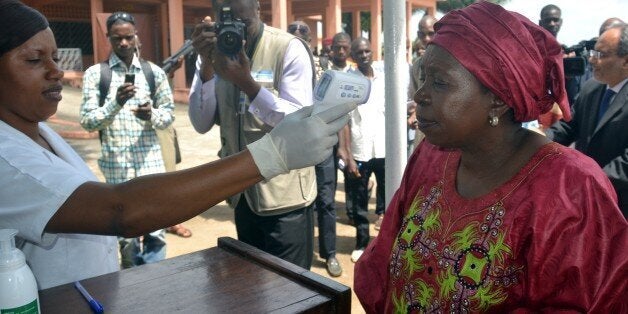 A health worker checks the temperature of African Union Chairperson Nkosazana Dlamini-Zuma as she arrives in Conakry on Octob