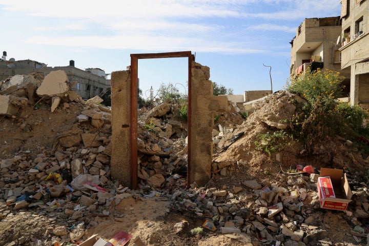 An empty frame doorway is seen standing on the rubble of a destroyed building that was damaged in last summer's Israel-Hamas