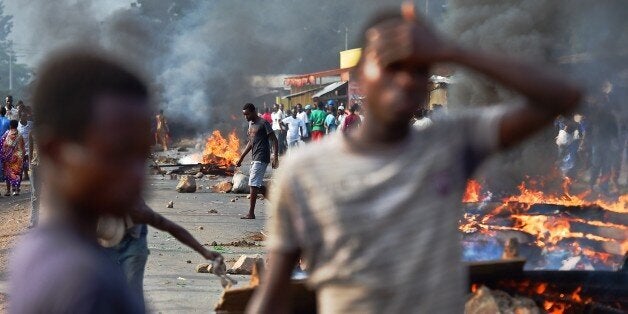 Protestors stands near a burning barricade during a demonstration against Burundian President's third term candidature in the Cibitoke neighborhood of Bujumbura on May 22, 2015. Thousands of anti-government protesters in Burundi marched on the streets of the capital Bujumbura, defying one of the heaviest pushes by police to end weeks of demonstrations. AFP PHOTO/ CARL DE SOUZA (Photo credit should read CARL DE SOUZA/AFP/Getty Images)