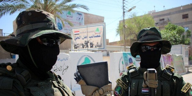 Iraqi fighters of the Shiite militia Asaib Ahl al-Haq (The League of the Righteous) stand guard outside their headquarters on May 18, 2015 in the Iraqi mainly Shiite southern city of Basra, as Shiite militias converged on Ramadi in a bid to recapture it from jihadists who dealt the Iraqi government a stinging blow by overrunning the city in a deadly three-day blitz. 'When it comes to readiness, we have more than 3,000 fighters waiting for a signal from the secretary general (of Asaib) Sheikh Qais al-Khazali,' spokesman Jawad al-Talabawi said. AFP PHOTO / HAIDAR MOHAMMED ALI (Photo credit should read HAIDAR MOHAMMED ALI/AFP/Getty Images)