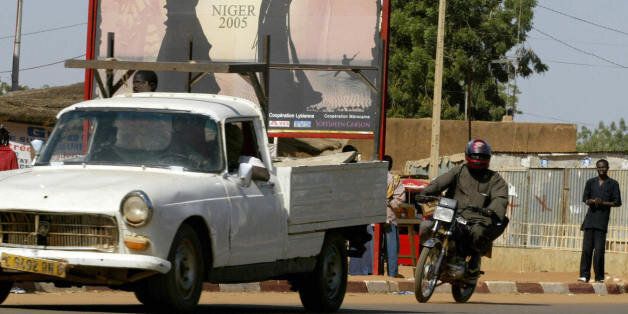 Niamey, NIGER: Vehicles drive past a board announcing the International Festival of African Fashion (FIMA), 01 December 2005, in Niamey. The 5th festival, created by Niger's fashion designer Seidnaly Sidhamed Alphadi, is dedicated to the fight against child malnutrition. The food crisis is the result of drought and invasions by locust swarms, though the president and his prime minister disagree over whether it was a famine or local food shortages. AFP PHOTO SEYLLOU (Photo credit should read SEYLLOU/AFP/Getty Images)