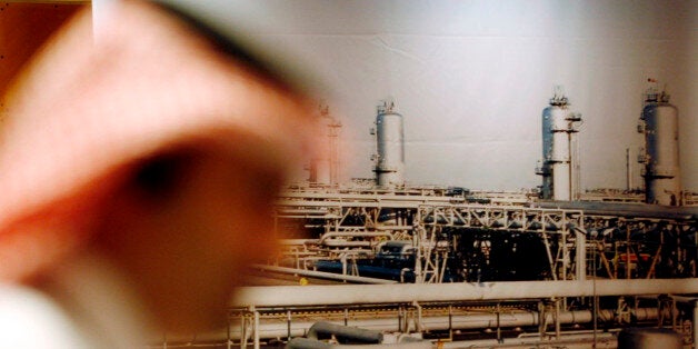 A Saudi official stands in front of a giant Saudi oil industry picture at a hotel in the Red Sea port city of Jiddah, Saudi A