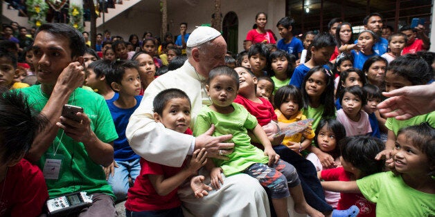 Pope Francis sits with children of the Anak-Tnk Foundation, founded in 1998 by a Jesuit priest, which helps homeless children and those living in the slums, in Manila's Intramuros district after celebrating Mass at the nearby Manila Cathedral, in Manila, Philippines, Friday, Jan. 16, 2015. Some 300 children at a Manila center for street kids got the surprise of their lives on Friday when Pope Francis showed up at their door. (AP Photo/Osservatore Romano, Pool)