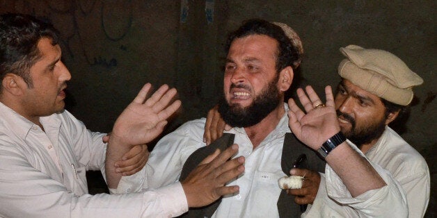 People comfort a man, mourning the death of his relative, killed by gunmen when they hijacked two buses, at a local hospital in Saturday, May 30, 2015 in Quetta, Pakistan. Officials say Pakistani security forces have launched a major operation to hunt down gunmen who hijacked two buses and killed more than a dozen passengers in the country's southwest before fleeing. (AP Photo/Arshad Butt)