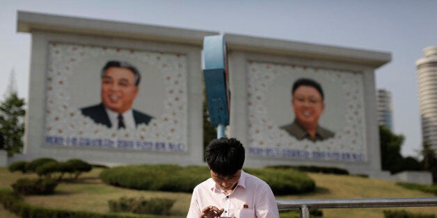 In this Tuesday, May 5, 2015, photo, a man sits in front of portraits of the late North Korean leaders Kim Il Sung, left, and