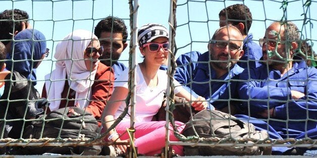 Migrants sit onboard the Godetia logistical support ship of the Belgian Navy on May 30, 2015 upon its arrival in the port of