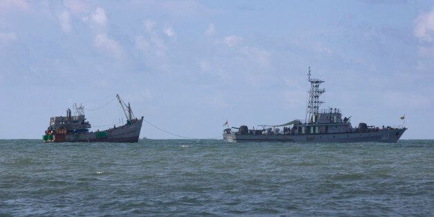A Myanmar navy boat, with migrants-onboard, tows a boat with migrants off Myanmar's Thameehla island, south of Irrawaddy division, Sunday, May 31, 2015. The wooden boat was one of more than half-dozen that have either washed to Southeast Asian shores or been rescued in the last month following a massive, regional crackdown on human trafficking networks. (AP Photo/Gemunu Amarasinghe)