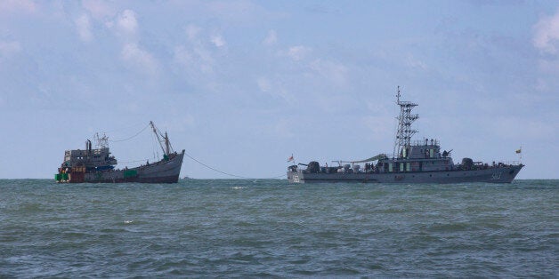 A Myanmar navy boat, with migrants-onboard, tows a boat with migrants off Myanmar's Thameehla island, south of Irrawaddy divi