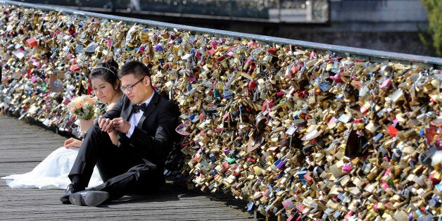 FILE - This Wednesday April 16, 2014 file photo shows a newly wed couple resting on the Pont des Arts in Paris, France. Any hope that the love locks that cling to Parisâ famed Pont des Arts bridge would last forever _ will be unromantically dashed by the city council who plan to dismantle them Monday _ for good. (AP Photo/Remy de la Mauviniere, File)