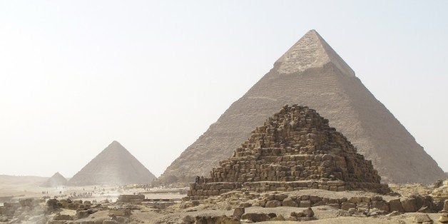 In this Tuesday, Feb. 3, 2015 photo, stray dogs rest in front of the Pyramids of Giza on the outskirts of Cairo, Egypt. Touri