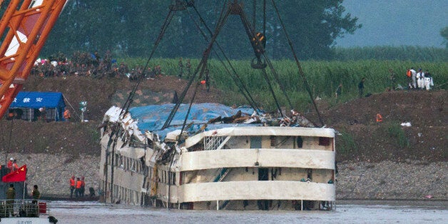 Rescuers watch the capsized ship Eastern Star being lifted by cranes on the Yangtze River in Jianli county of southern Chinaâs Hubei province, as seen from across the river from Huarong county of southern Chinaâs Hunan province, Friday, June 5, 2015. The Eastern Star's top-deck cabins with smashed blue roofs jutted out of gray water Friday after Chinese disaster teams righted the capsized river cruiser to ease the search for people still missing. (AP Photo/Andy Wong)