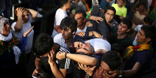 A youth is carried after being wounded in an explosion at a pro-Kurdish Peopleâs Democratic Party (DHP) rally in Diyarbakir, southeastern Turkey, Friday, June 5, 2015 ahead of the general election on June 7, 2015. At least 10 people were injured in two explosions five minutes apart at the rally, attended by thousands of people. The explosions occurred at the party's final election rally in Diyarbakir _ the main city in Turkeyâs predominantly Kurdish southeast _ as the partyâs leader Selahattin Demirtas was preparing to address the crowd. (AP Photo/Emre Tazegul)