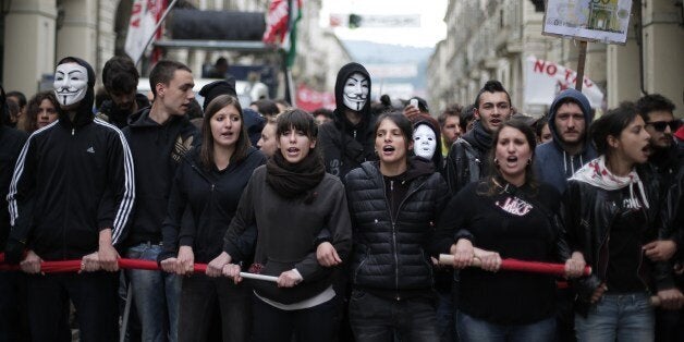 Demonstrators face policemen in Turin during one of several rallies against unemployment and austerity in Italy for May Day, on May 1, 2014. Activists lobbed smoke bombs at police, who charged against the demonstrators in an industrial city that has been badly hit by a painful two-year recession. Thousands also took part in a peaceful demonstration called by the main trade unions in Pordenone, where the closure of a nearby washing machine plant owned by Sweden's Electrolux is putting 1,300 jobs at risk. AFP PHOTO / MARCO BERTORELLO (Photo credit should read MARCO BERTORELLO/AFP/Getty Images)