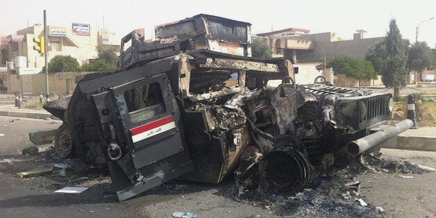 FILE - In this Thursday, June 12, 2014 file photo, an Iraqi army armored vehicle is seen burned on a street of the northern c