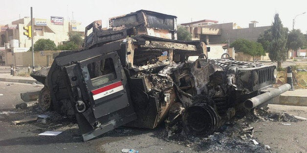 FILE - In this Thursday, June 12, 2014 file photo, an Iraqi army armored vehicle is seen burned on a street of the northern city of Mosul, Iraq. Iraqi Prime Minister Haider al-Abadi announced last month that at least 50,000 ghost soldiers had been identified in four different divisions of the military and cut from the military payroll. âWe were paying salaries while we lack the money,â he said in a televised address. âWe have started blowing some big fish out of the water and weâll go after them until the end, even if it costs me my life and regardless of the campaigns I will be subjected to, because corruption is just as significant as terrorism."(AP Photo, File)