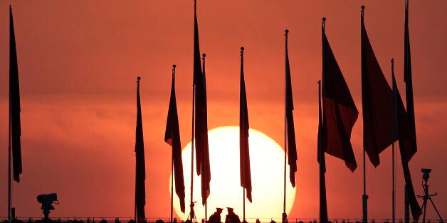 Chinese military personnel watch over Tiananmen Square from a rooftop across from the Great Hall of the People, as the sun ri