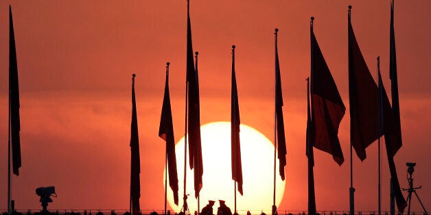 Chinese military personnel watch over Tiananmen Square from a rooftop across from the Great Hall of the People, as the sun rises before the opening session of the National People's Congress in Beijing Thursday, March 5, 2015. (AP Photo/Andy Wong)