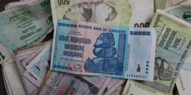 An old one hundred trillion Zimbabwean dollar note on top of a pile of other old Zimbabwean notes of various denominations