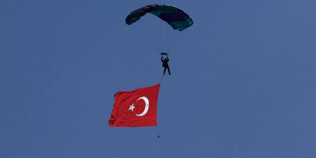 A Turkish parachutist with a Turkish flag flies over a military parade in the Turkish occupied area of the divided capital Ni