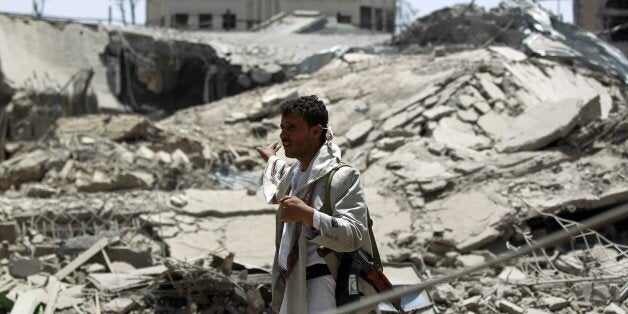 A Yemeni man stands near a collapsed building following an air-strike by the Saudi-led coalition in the capital Sanaa on June
