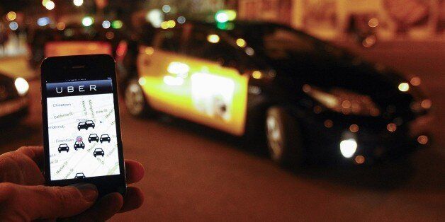 The Uber app is seen on a smartphone past cabs waiting for clients near the Sagrada Familia in Barcelona, on December 9, 2014. A judge on December 9, 2014 banned the popular smartphone taxi service Uber from operating in Spain, court officials said, following similar prohibition action in several other countries. AFP PHOTO/ QUIQUE GARCIA (Photo credit should read QUIQUE GARCIA/AFP/Getty Images)
