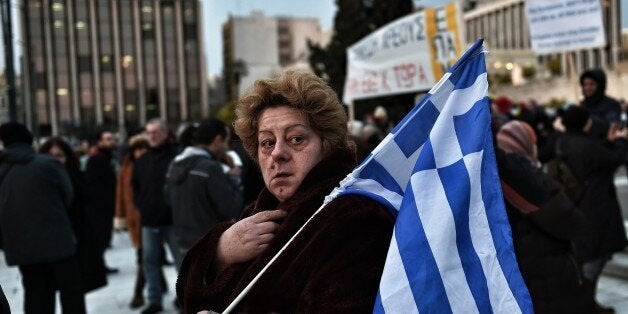 A woman holds a Greek flag as people demonstrate in front of the parliament to support the Greek government in Athens on February 11, 2015. Greece is to seek a cash lifeline at an emergency meeting of eurozone finance ministers on February 11, as Athens struggles to persuade its EU creditors to renegotiate its massive bailout deal. AFP PHOTO / ARIS MESSINIS (Photo credit should read ARIS MESSINIS/AFP/Getty Images)