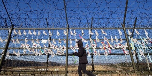 A South Korean tourist walks along a military barbed wire fence decorated with national flags at the Imjingak peace park at the border city of Paju near the Demilitarized Zone (DMZ) dividing the two Koreas on January 1, 2015. North Korean leader Kim Jong-Un said on January 1 he was open to the 'highest-level' talks with South Korea as he called for an improvement in strained cross-border relations. AFP PHOTO / JUNG YEON-JE (Photo credit should read JUNG YEON-JE/AFP/Getty Images)