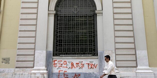 A pedestrian passes a sign reads ''Out of EU (European Union)'' at the headquarters of National Bank of Greece in Athens, Wednesday, June 10, 2015. Greeceâs prime minister was heading to Brussels on Wednesday hoping to meet with the leaders of Germany and France, in an effort to break a deadlock in bailout talks that have revived fears his country could default and drop out of the euro. (AP Photo/Thanassis Stavrakis)