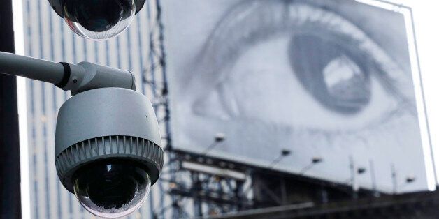 Security cameras are mounted on the side of a building overlooking an intersection in midtown Manhattan, Wednesday, July 31, 2013 in New York. In the background is a billboard of a human eye. (AP Photo/Mark Lennihan)