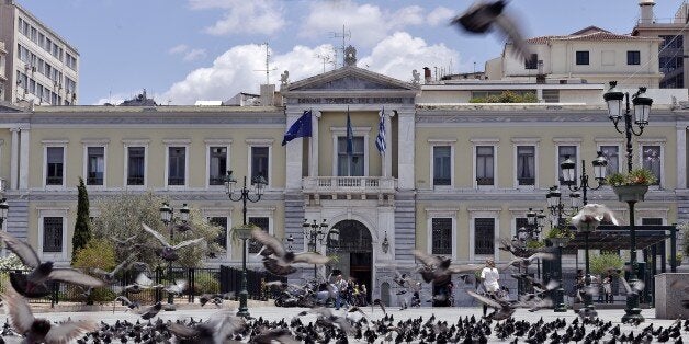 Pigeons fly in front of the National Bank of Greece headquarters in central Athens on June 23, 2015. Hopes that Greece and its creditors can seal a debt deal with exactly one week left to avert default could fade as the Greek premier faces pressure to convince his anti-austerity party to approve concessions needed to unblock bailout funds. AFP PHOTO / LOUISA GOULIAMAKI (Photo credit should read LOUISA GOULIAMAKI/AFP/Getty Images)