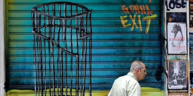 An elderly man passes graffiti in Athens, Friday, June 26, 2015. With Greece facing a potential debt default June 30, European leaders have demanded finance ministers from eurozone countries reach an agreement on Saturday that will allow creditors to unblock the remaining 7.2 billion euros in Greece's international bailout program. (AP Photo/Thanassis Stavrakis)