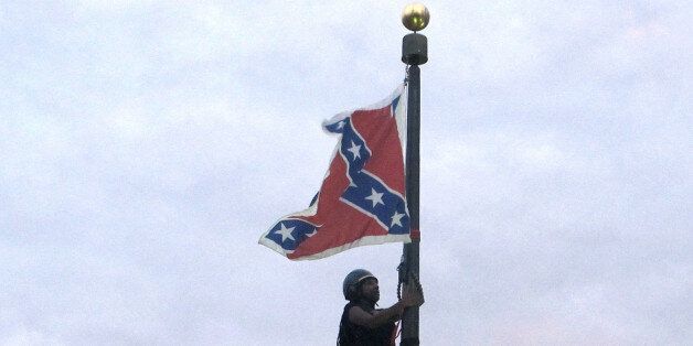 Bree Newsome of Charlotte, N.C., climbs a flagpole to remove the Confederate battle flag at a Confederate monument in front of the Statehouse in Columbia, S.C., on Saturday, June, 27, 2015. She was taken into custody when she came down. The flag was raised again by capitol workers about 45 minutes later. (AP Photo/Bruce Smith)