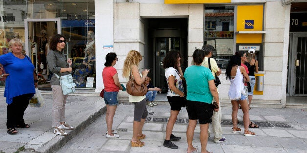 People line up at an ATM outside a Piraeus bank branch in Athens, Monday, June 29, 2015. Anxious Greeks lined up at ATMs as they gradually began dispensing cash again on the first day of capital controls imposed in a dramatic twist in Greeceâs five-year financial saga. Banks will remain shut until next Monday, and a daily limit of 60 euros ($67) has been placed on cash withdrawals from ATMs. (AP Photo/Thanassis Stavrakis)