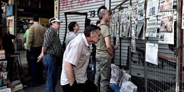 People read newspapers in central Athens on June 30, 2015. European leaders want to 'sink' Greece's ruling Syriza party to block the rise of other far-left anti-austerity parties like its ally Podemos in Spain, Greece's Labour Minister Panos Skourletis said Tuesday. AFP PHOTO / ARIS MESSINIS (Photo credit should read ARIS MESSINIS/AFP/Getty Images)