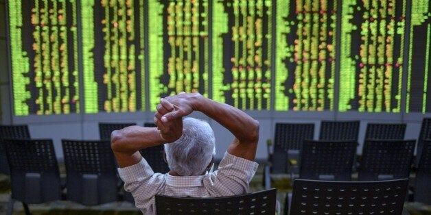 A man gestures as he monitors stock movements at a private trading firm in Kuala Lumpur on June 30, 2015. Most Asian markets edged higher on June 30, enjoying a slight recovery after the previous day's rout, with Greece just hours away from default, while Shanghai ended flat after another highly volatile morning. AFP PHOTO / MOHD RASFAN (Photo credit should read MOHD RASFAN/AFP/Getty Images)