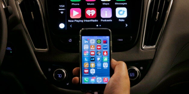 An iPhone is connected to a 2016 Chevrolet Malibu equipped with Apple CarPlay apps, displayed on the car's MyLink screen, top, during a demonstration in Detroit, Tuesday, May 26, 2015. Starting with Chevrolet this summer, many General Motors models will offer Appleâs CarPlay and Googleâs Android Auto systems that link smart phones with in-car screens and electronics. (AP Photo/Paul Sancya)