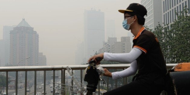 This picture taken on June 23, 2015 shows a cyclist wearing a mask in Beijing covered by heavy smog. China's cities are often hit by heavy pollution, blamed on coal-burning by power stations and industry, as well as vehicle use. The issue has become a major source of popular discontent with the Communist Party, leading the government to vow to reduce the proportion of energy derived from fossil fuels. CHINA OUT AFP PHOTO (Photo credit should read STR/AFP/Getty Images)