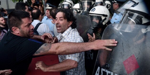 Anti-EU protesters scuffle with police outside the European Comission offices in Athens on July 2, 2015. Greece's government and international creditors raised the stakes on July 2 over a weekend referendum seen as decisive for the nearly insolvent EU country's political and financial future. While Prime Minister Alexis Tsipras has urged Greeks to vote 'No' to the austerity measures demanded by international creditors, opposition parties including the centre-right New Democracy are campaigning for a 'Yes' vote in the referendum on July 5. AFP PHOTO / Louisa Gouliamaki (Photo credit should read LOUISA GOULIAMAKI/AFP/Getty Images)