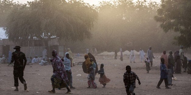 Civilians who fled the fighting in Bama and the surrounding areas in recent days walk at a makeshift camp for displaced peopl