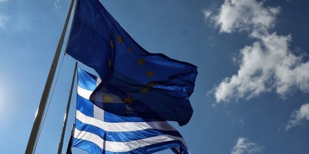 An European Union and Greek flags fly in central Athens on July 4, 2015. Nearly 10 million Greek voters will take to the ballot booths Sunday to vote 'Yes' or 'No' in a referendum asking if they accept more austerity measures in return for bailout funds. AFP PHOTO/ LOUISA GOULIAMAKI (Photo credit should read LOUISA GOULIAMAKI/AFP/Getty Images)