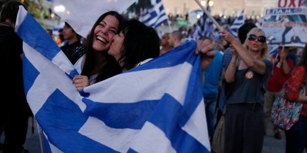 Supporters of the No vote react after the first results of the referendum at Syntagma square in Athens, Sunday, July 5, 2015. Greece faced an uncharted future as its interior ministry predicted Sunday that more than 60 percent of voters in a hastily called referendum had rejected creditors' demands for more austerity in exchange for rescue loans. (AP Photo/Petros Giannakouris)