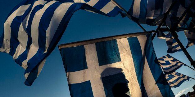 A pro-Euro demonstrator isÂ silhouettedÂ behind a Greek flag during a rally outside the Greek Parliament in Athens, Monday, June 22, 2015. Thousands of people gather to show support for the country's future in the eurozone and the European Union. (AP Photo/Daniel Ochoa de Olza)