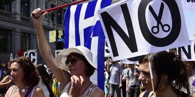 A woman holds a placard reading 'No cuts' during a demonstration in support of Greece, in Madrid on July 5, 2015. Today, nearly 10 million Greek voters take to the ballot booths to vote 'Yes' or 'No' in a referendum asking if they accept more austerity measures in return for bailout funds. The referendum on a deal with European governments, the European Union (EU) and International Monetary Fund (IMF), was called by Prime Minister Alexis Tsipras on the night of June 26-27. AFP PHOTO/ JAVIER SORIANO (Photo credit should read JAVIER SORIANO/AFP/Getty Images)