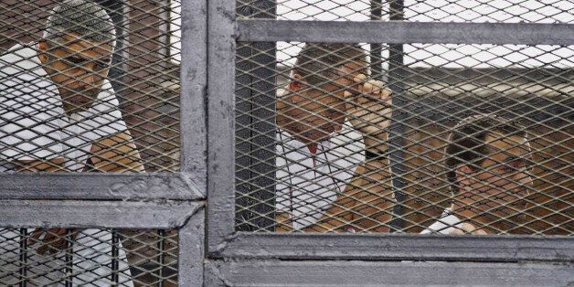 FILE - In this Thursday, May 15, 2014 file photo, from left, Mohammed Fahmy, Canadian-Egyptian acting bureau chief of Al-Jazeera, Australian correspondent Peter Greste, and Egyptian producer Baher Mohamed appear in a defendant's cage along with several other defendants during their trial on terror charges at a courtroom in Cairo. Egyptâs state news agency says the trial of three Al-Jazeera English journalists and 17 others has adjourned until next week when the judge will deliver the verdict, five months after the trial opened. Fahmy, Greste and Baher have been in detention since December 29. (AP Photo/Hamada Elrasam, File)