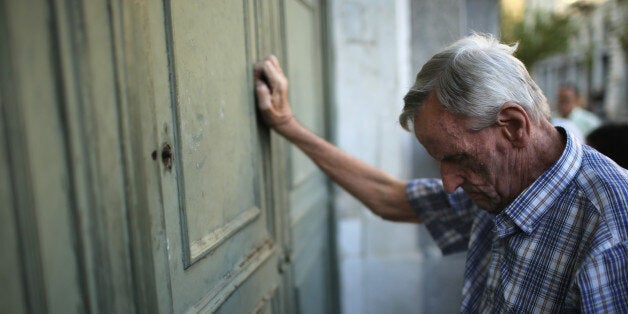 ATHENS, GREECE - JULY 07: A senior citizen leans against the door of a closed bank as he queues up to collect his pension outside a National Bank of Greece branch in Kotzia Square on July 7, 2015 in Athens, Greece. Greek Prime Minister Alexis Tsipras is working on new debt crisis proposals and is due to present them at a Eurozone emergency summit today. (Photo by Christopher Furlong/Getty Images)