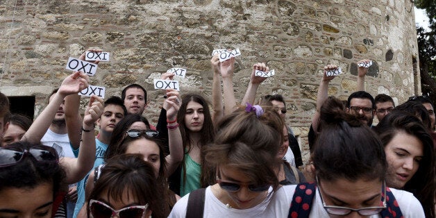 Members of the youth wing of the governing radical left Syriza party hold papers calling for a ''No'' vote in the referendum in the northern Greek city of Thessaloniki on Saturday, June 27, 2015. Greece's fraught bailout talks with its creditors took a dramatic turn early Saturday, with the radical left government announcing a referendum in just over a week on the latest proposed deal â and urging voters to reject it. (AP Photo/Giannis Papanikos)